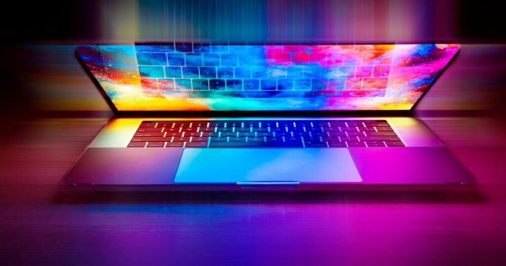 カラフルなグラデーションが映る開いたノートパソコンの画面とキーボード