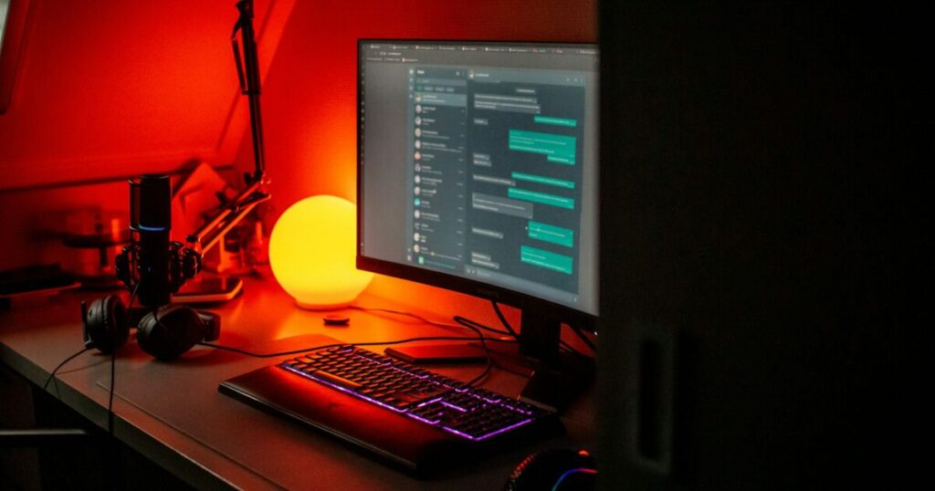 チャットアプリが表示されたモニターとゲーミングデスク環境